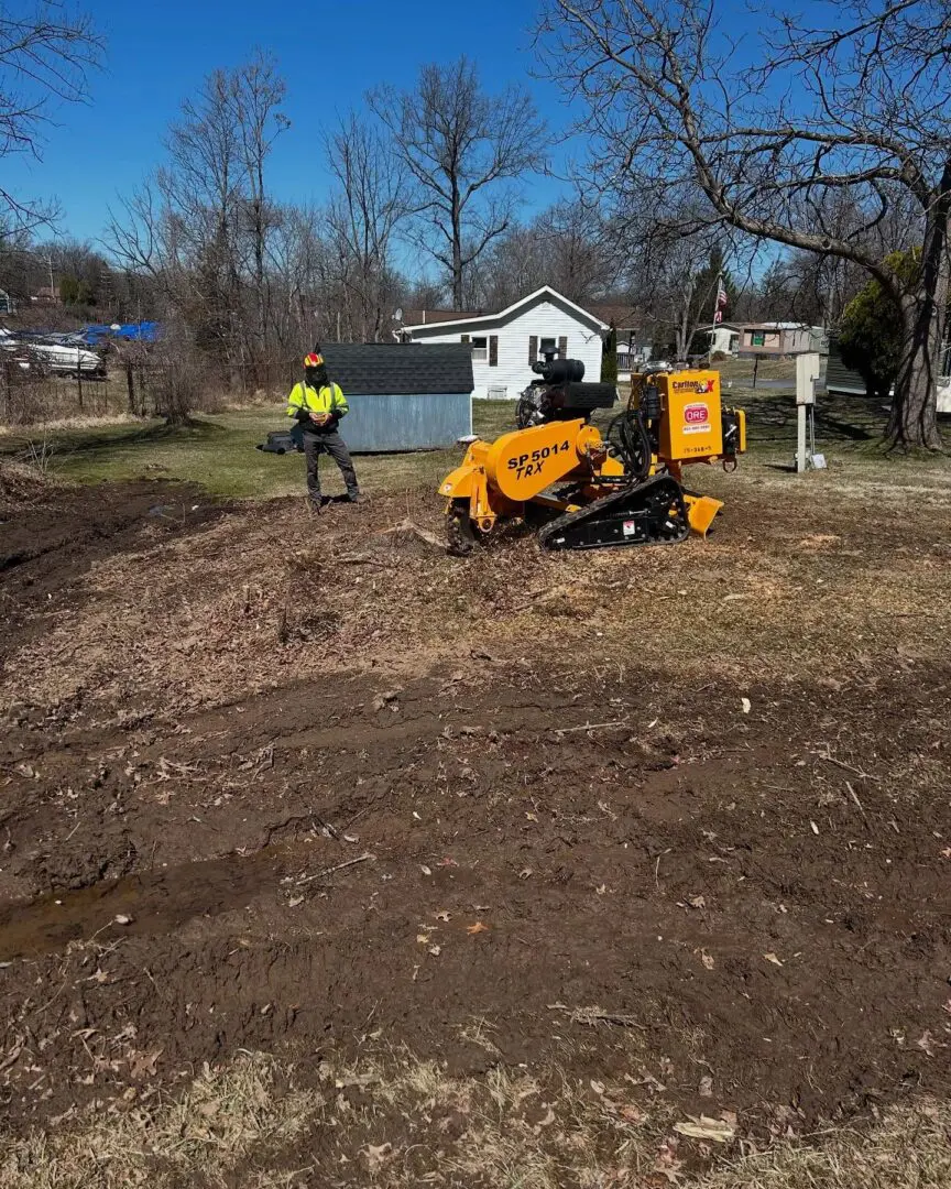 A person standing next to a stump grinder.