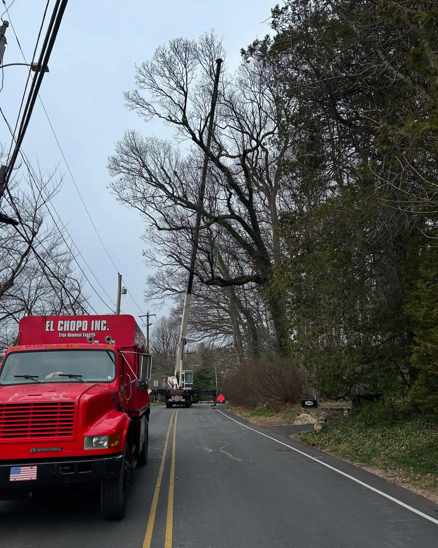 A red truck driving down the road near power lines.